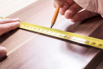 Carpenter Measuring A Wooden Board And Making A Mark With A Pencil