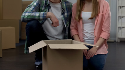 Couple in love sitting in new apartment, unpacking stuff, youth housing program