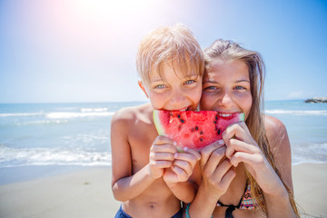 Adorable kids with watermelon on the beach.