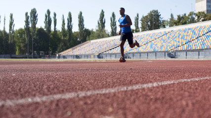 Purposeful Hispanic athlete running at stadium, preparing for marathon, sport