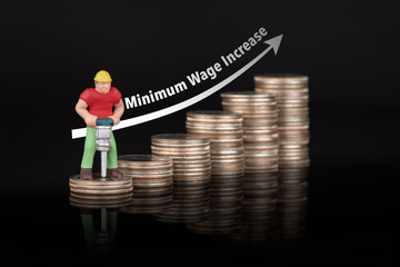 Miniature worker drilling on stacked US quarter coins with black background and  white illustration shows increasing of minumum wage.