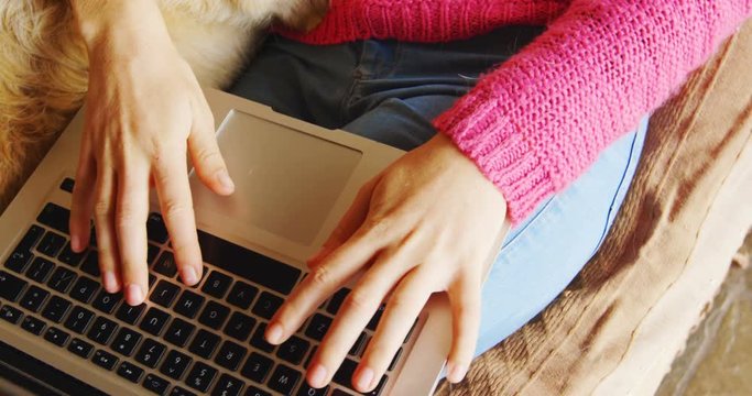 Woman using laptop with her dog on sofa 4k
