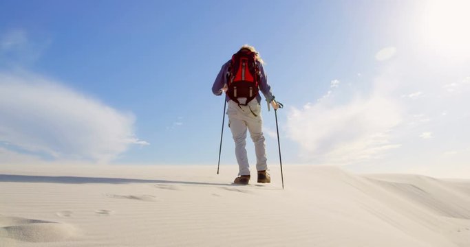 Man with hiking pole walking in the desert 4k