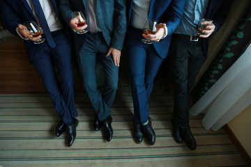 men in suits hold glasses with alcohol