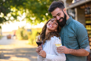 Portrait of young smiling man and woman tasting wine at winery vineyard - Young people enjoying harvest time together. Romantic love. - obrazy, fototapety, plakaty