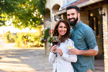 Portrait of young smiling man and woman tasting wine at winery vineyard - Young people enjoying harvest time together. Romantic love. - obrazy, fototapety, plakaty