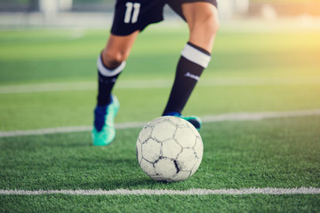 Soccer player speed run to shoot ball to goal on artificial turf.