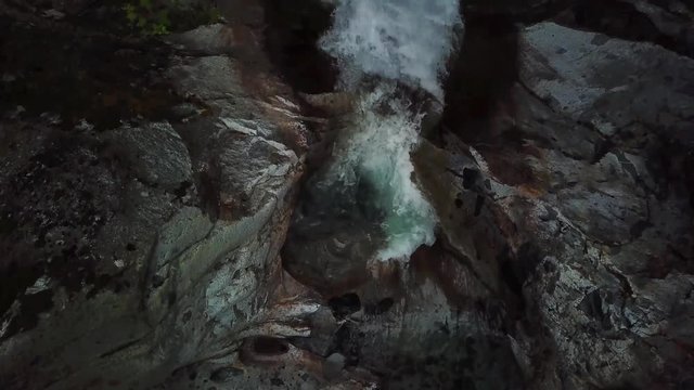 A drone shot oa a waterfall slowly revealing the bottom of the falls from top view