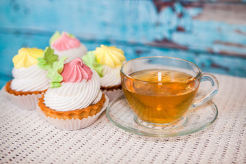 Cupcakes and cup of tea on blue wooden background, sweet food with hot drink