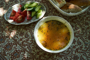 Traditional Azerbaijan dushbere soup with meat dumplings and fresh vegetable sliced tomatoes, cucumbers and pita bread