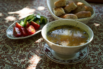 Traditional Azerbaijan dushbere soup with meat dumplings and fresh vegetable sliced tomatoes, cucumbers and pita bread