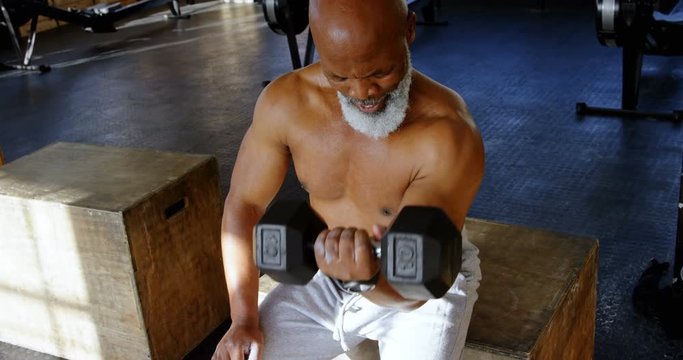 Senior man exercising with dumbbells in the fitness studio 4k