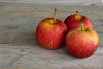 three apples on wooden table