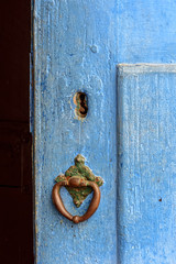 Old and aged blue historic church wooden door in the city of Sabara, Minas Gerais with its rusty metal part.