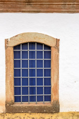 Old church window made of wood in colonial style with frame in stone in Sabara city, Minas Grerais, Brazil