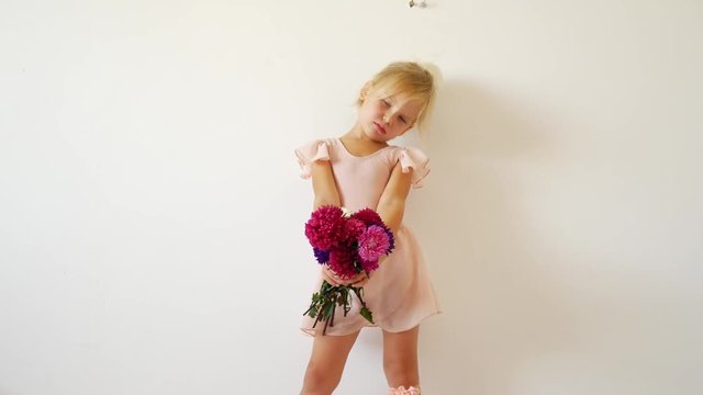 Young dancer posing with a bouquet of flowers. Happy little ballerina.