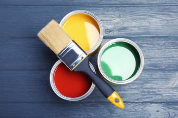 Flat lay composition with paint cans and brush on wooden background