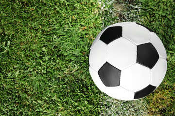 Fototapeta na wymiar Soccer ball on fresh green football field grass, top view. Space for text
