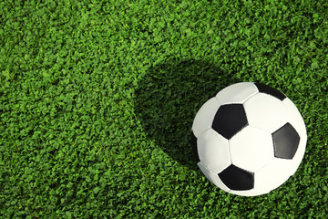 Soccer ball on fresh green football field grass, top view. Space for text