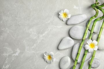 Fototapeta na wymiar Bamboo branches, spa stones and flowers on gray background, top view. Space for text