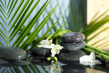 Fototapeta na wymiar Spa stones, flowers and bamboo branches in water