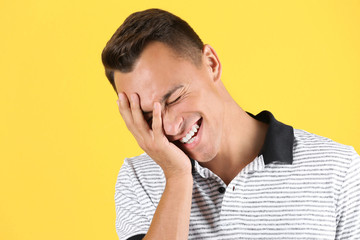 Portrait of handsome young man laughing on color background