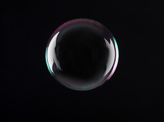 Beautiful translucent soap bubble on dark background. Space for text