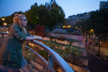 Beautiful girl looks into the distance in the lights of the evening Paris