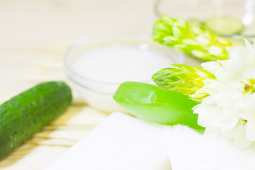 Cucumber home spa and hair care concept. Sliced cucumber, bottles of oil, grean soap, bathroom towel. Straw light background