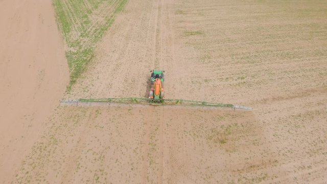 aerial view of an old tractor spraying pesticides on an agricultural field