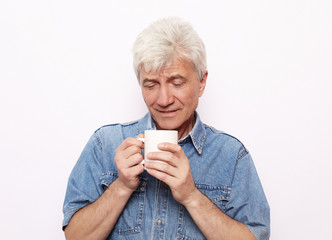 lifestyle, food and people concept: Handsome mature man hoding a cup of coffee or tea