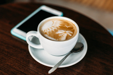 Cup of hot latte art coffee on wooden table