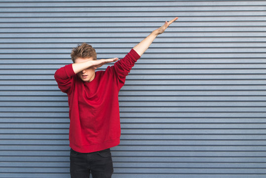 Young man throws dab on the background of a gray wall.