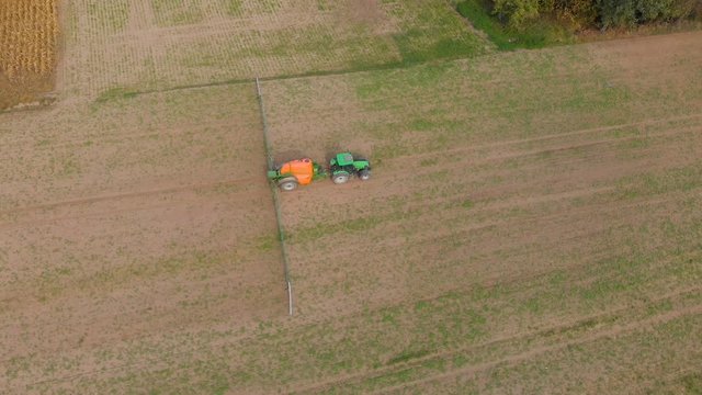 aerial view of an old tractor spraying pesticides on an agricultural field