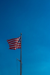 National flag of United States flying against blue sky