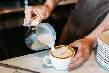Fototapeta na wymiar Barista pouring latte foam over coffee, espresso and creating a perfect latte art