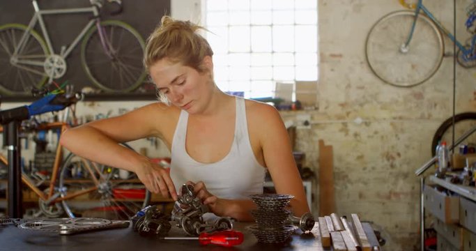 Woman repairing parts of bicycle at workshop 4k