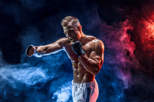 Studio portrait of fighting muscular man in smoke on dark background