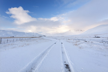 Lonely winter road./ Amazing landscape with country road, mountains and snow in south Iceland