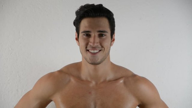 Handsome shirtless athletic young man in jeans, looking at camera in studio shot, on white background
