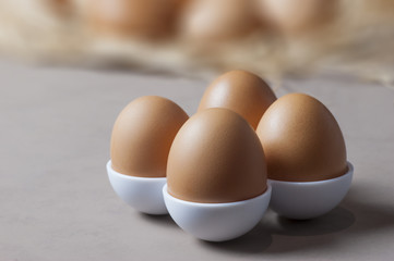 Brown or yellow Fresh farm eggs on quaternary eggcup, eggs background
