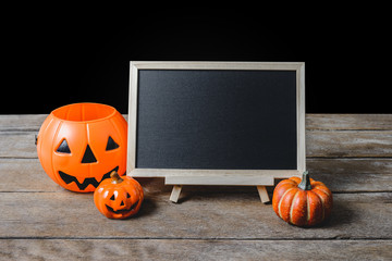 The chalkboard on the stand with Halloween Pumpkins on wooden floor and black background
