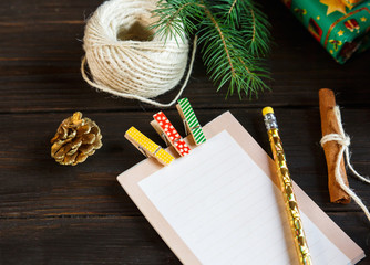 blank notepad lays on the wooden background to make a list of presents for friends and family or write resolution for next year. New year and Christmas concept