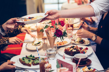 Waiter serve the clients table and gives plate with fruit sald on Sunday family brunch