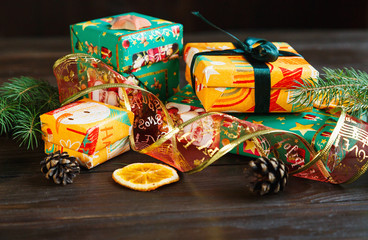Fototapeta na wymiar presents in orange and green paper on the wooden background for friends and family. shopping, New year and Christmas concept. close up