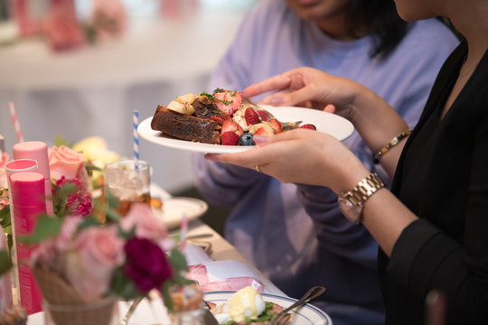 Woman taking toast with fruit salad in a restaurant and talking with her friend - Powered by Adobe