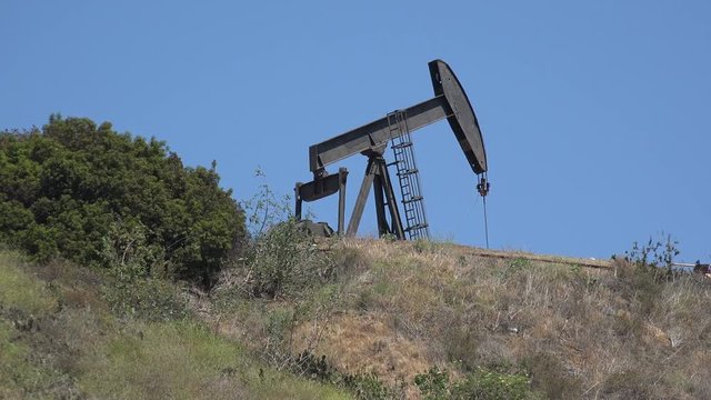 An oil pump jack pumping on top of a hill