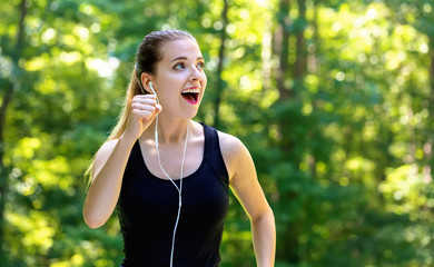 Athletic young woman jogging on a bright summer day in the forest