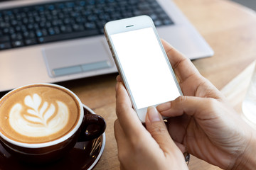 hand woman using a telephone, empty screen smart phone and computer on wooden table In the coffee shop. with clipping path