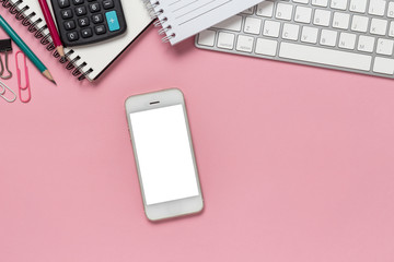 Top view office desk with empty smartphone, computer and office supplies on a pink background